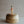 Small, clear glass bottle with a cork lid, filled with orange tipped matchsticks. The bottle is displayed atop a wood stand, four matches lay next to the bottle