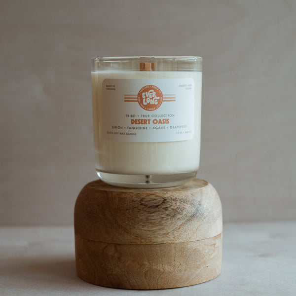 Everlong Candle Co. Desert Oasis candle (13oz) on a wooden stand.  Retro-inspired label with orange stripes. Vegan coconut-soy wax, crackling wood wick.