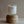 Clear glass jar candle on a wooden stand. White label with warm pink stripes, 